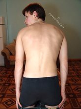 Dark-haired young boy shows off his body by the table