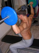 Muscular twink lifting weights in the gym before posing