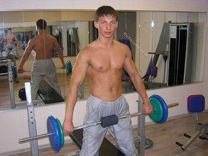 Muscular twink lifting weights in the gym before posing