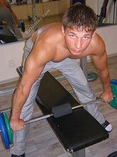 Muscular twink lifting weights in the gym before posing