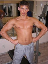 Muscular twink lifting weights in the gym before posing
