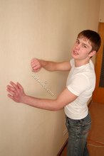 Leggy teen posing sexily with his back against the wall