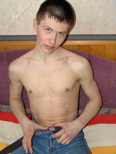 Shirtless twink posing seductively on a dirty sofa
