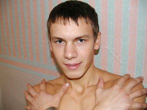 Shirtless twink poses with his back to the wall
