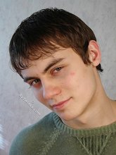 Smiling twink shows his hairy cock while resting on a bed