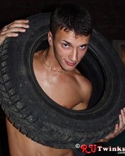 Dark-haired guy with a perfect body moving tires and looking hot