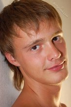Young guy smiles coyly while staring into the camera, naked