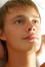 Young guy smiles coyly while staring into the camera, naked