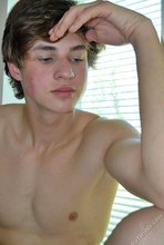 Dark-haired guy with a hairy cock posing by the window