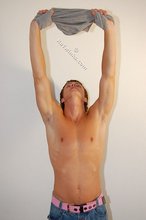 Blond-haired boy smiles at the camera while stripping for you