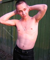 Serious-looking twink takes off his shirt outdoors