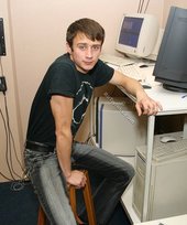 Dark-haired dude with beautiful eyes poses in his room