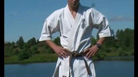 Karate black belt slowly undressing next a river